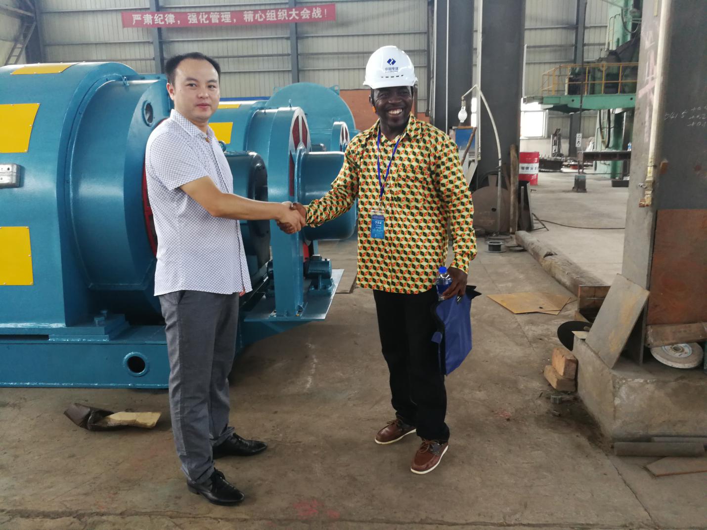 African engineer shaking hands with TC HYDRO staff in front of Francis turbine
