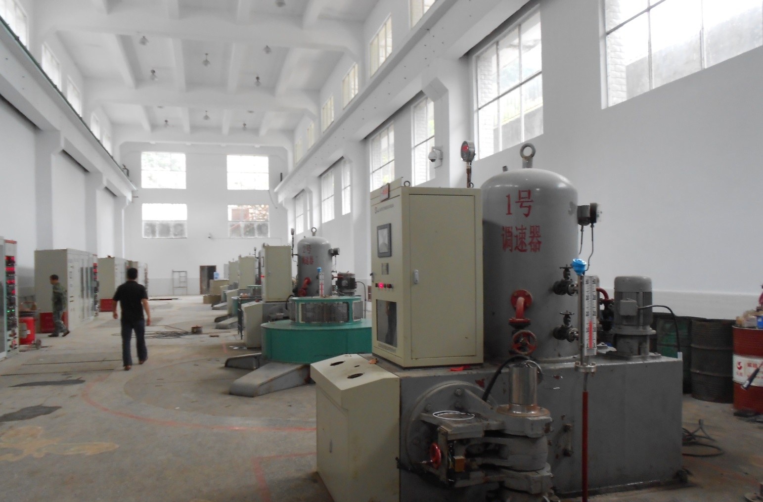 Machine hall at Zhuyuan hydropower plant with governor pressure oil tank and unit-side control cabinets